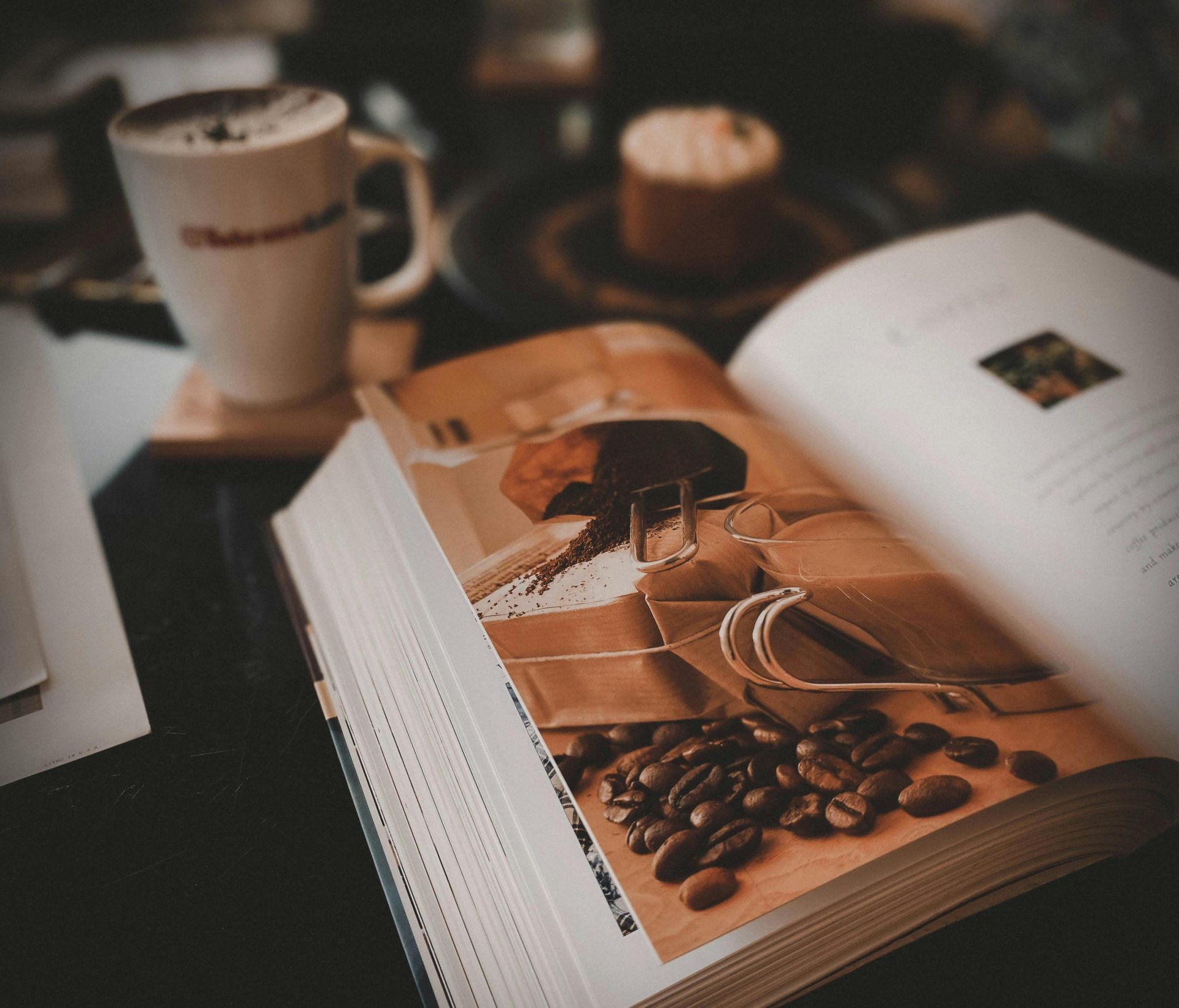 Warm coffee shop setup with an open book, latte, and cake, perfect for relaxation.